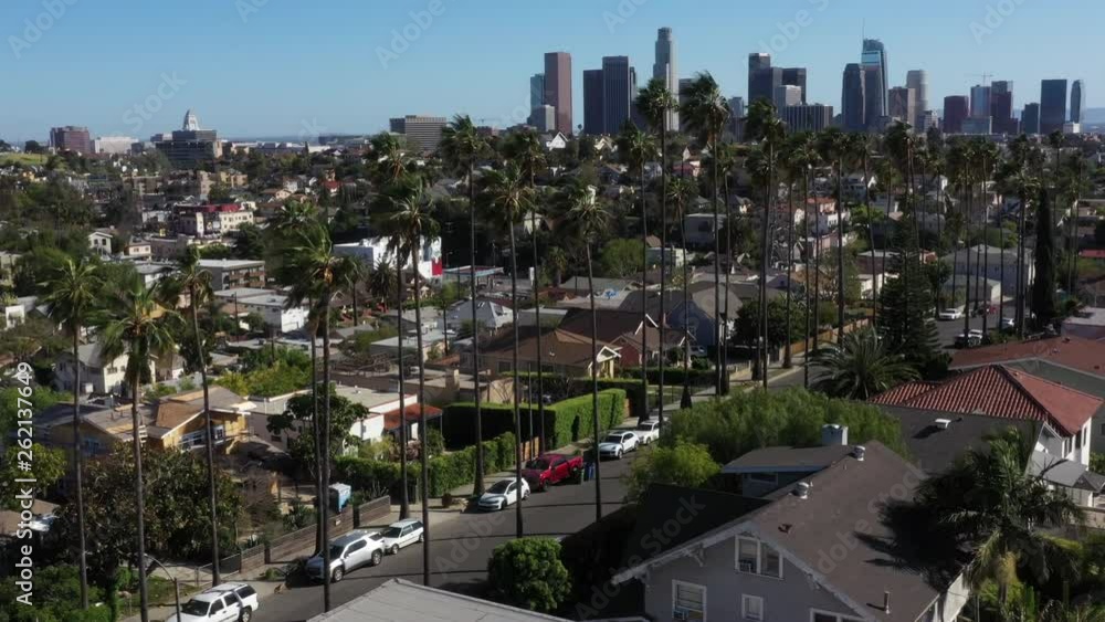 Drone flys over iconic Los Angeles palm tree lined street with the city skyline in the background. Drone flys over iconic Los Angeles palm tree lined street with the city skyline in the background.