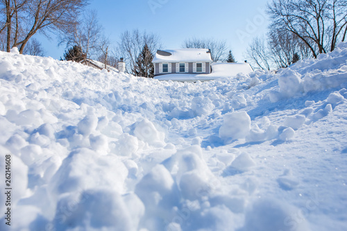 Fotografie Snow drifts and chunks of snow piling up in winter with a house in the backgroun