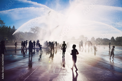 Silhouette of people playing in a splash park fountain