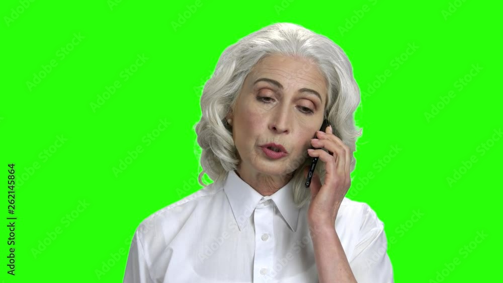 Serious elderly woman talking on phone. Portrait of confident mature woman talking on cell phone. Green Chroma Key background for keying. Serious elderly woman talking on phone. Portrait of confident mature woman talking on cell phone. Green Chroma Key background for keying.