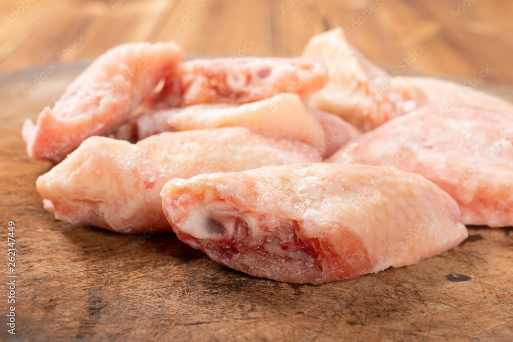 side view frozen raw chicken wings on chop board side view frozen raw chicken wings on chop board