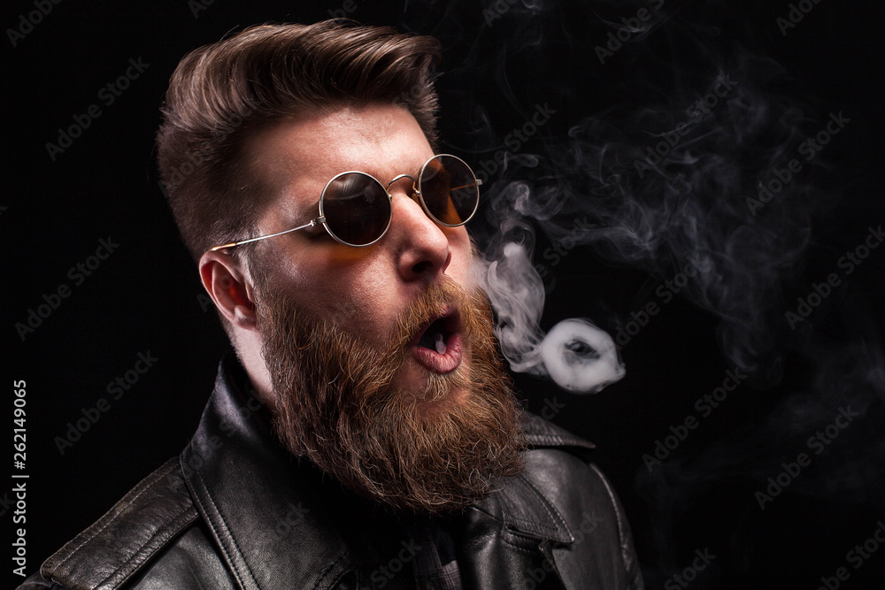 Portrait of bearded hipster man making smoke circles over black background Portrait of bearded hipster man making smoke circles over black background