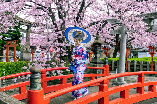 Fototapeta Azjatycka kobieta jest ubranym japońskiego tradycyjnego kimono i czereśniowego okwitnięcie w wiośnie, Kyoto świątynia w Japonia.
