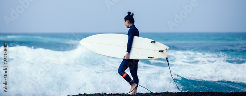 Photography Woman surfer with surfboard going to surf