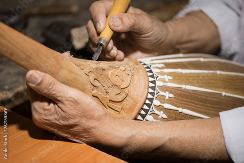 Fotografie adult master restores old musical instruments. wood carving