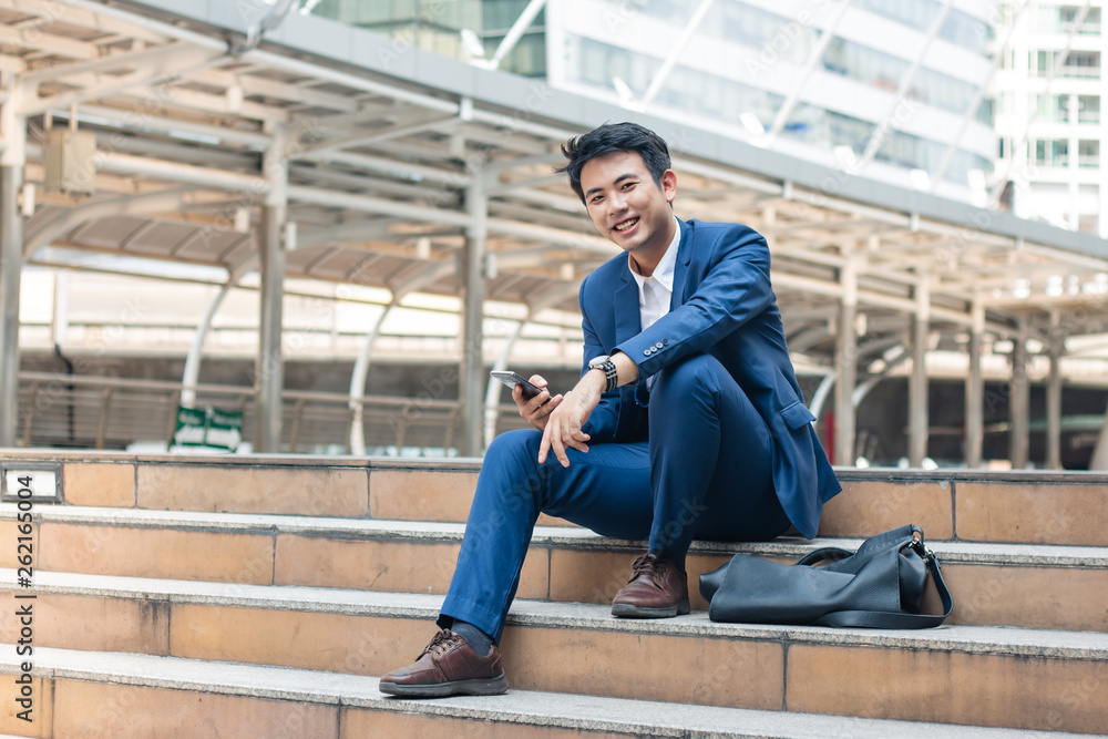 Smart young businessman carry his smart phone and smile.