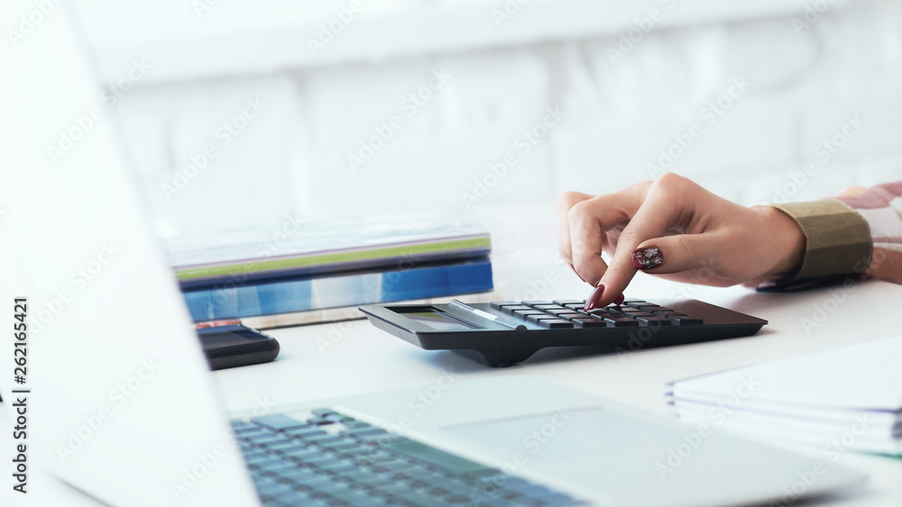Close up of woman hands with calculator counting and taking notes to laptop. Job of an accountant freelancer for the calculation of tax deductions. Close up of woman hands with calculator counting and taking notes to laptop. Job of an accountant freelancer for the calculation of tax deductions.