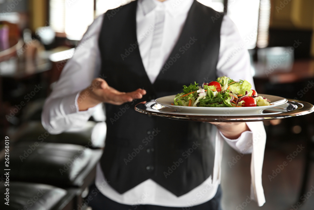 Young female waiter with salad in restaurant, closeup Young female waiter with salad in restaurant, closeup