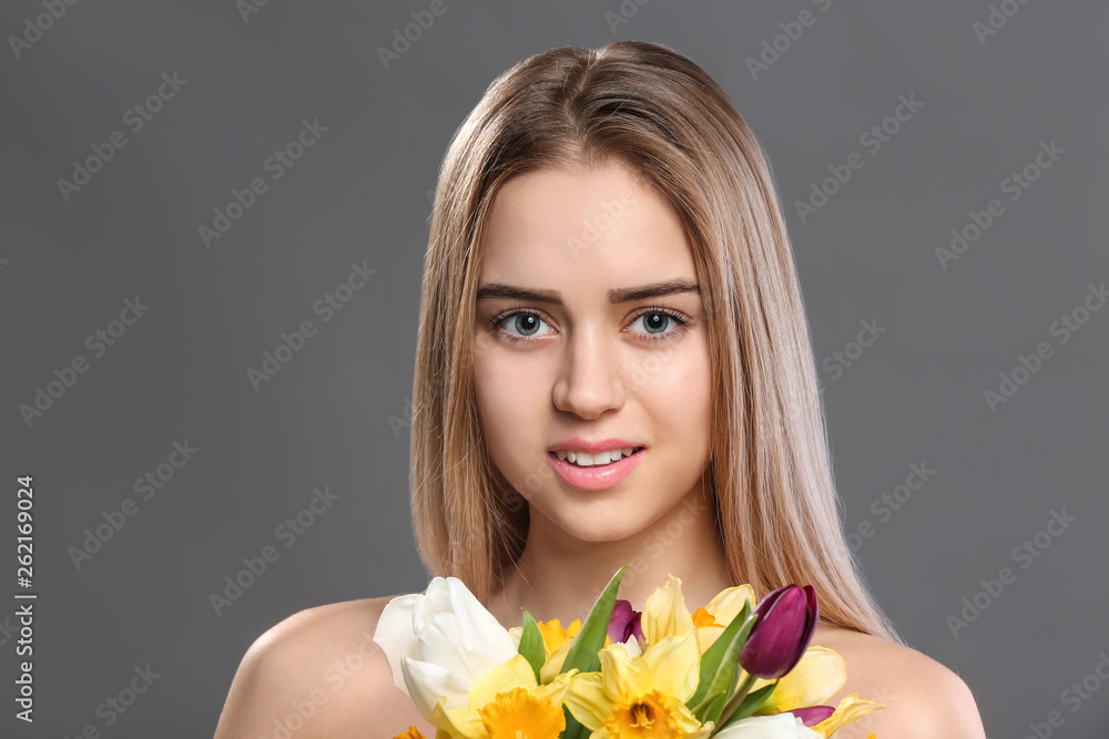 Beautiful young woman with laminated eyelashes and flowers on grey background Beautiful young woman with laminated eyelashes and flowers on grey background