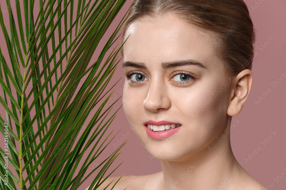 Beautiful young woman with laminated eyelashes and tropical leaves on color background Beautiful young woman with laminated eyelashes and tropical leaves on color background