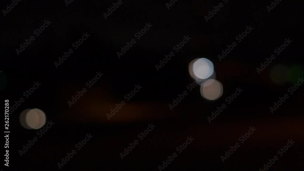 Car headlights out of focus, bokeh balls moving, night time Car headlights out of focus, bokeh balls moving, night time