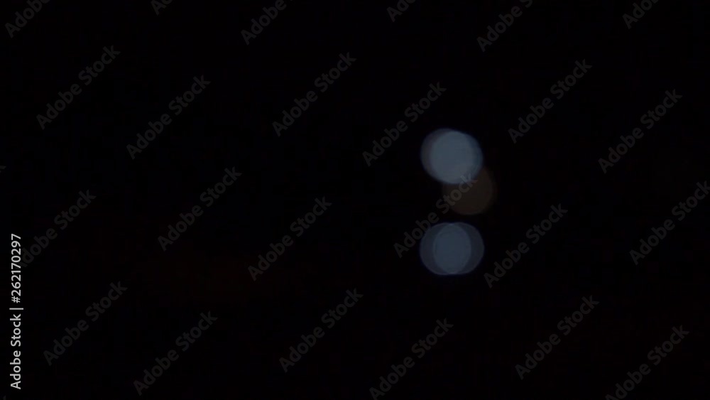 Car headlights out of focus, bokeh balls moving, night time Car headlights out of focus, bokeh balls moving, night time