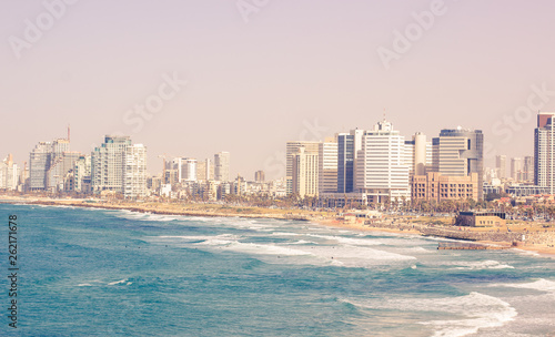 Tel Avivi Israel capital city view Mediterranean sea waterfront sand beach along vivid blue water with waves and high skyscrapers buildings, summer travel and vacation wallpaper concept