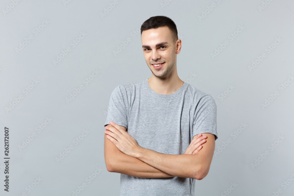 Portrait of smiling handsome young man in casual clothes looking camera, holding hands crossed isolated on grey background in studio. People sincere emotions, lifestyle concept. Mock up copy space. Portrait of smiling handsome young man in casual clothes looking camera, holding hands crossed isolated on grey background in studio. People sincere emotions, lifestyle concept. Mock up copy space.