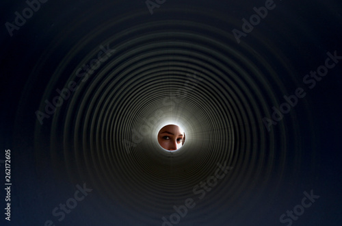 woman eyes looking through a black plastic pipe
