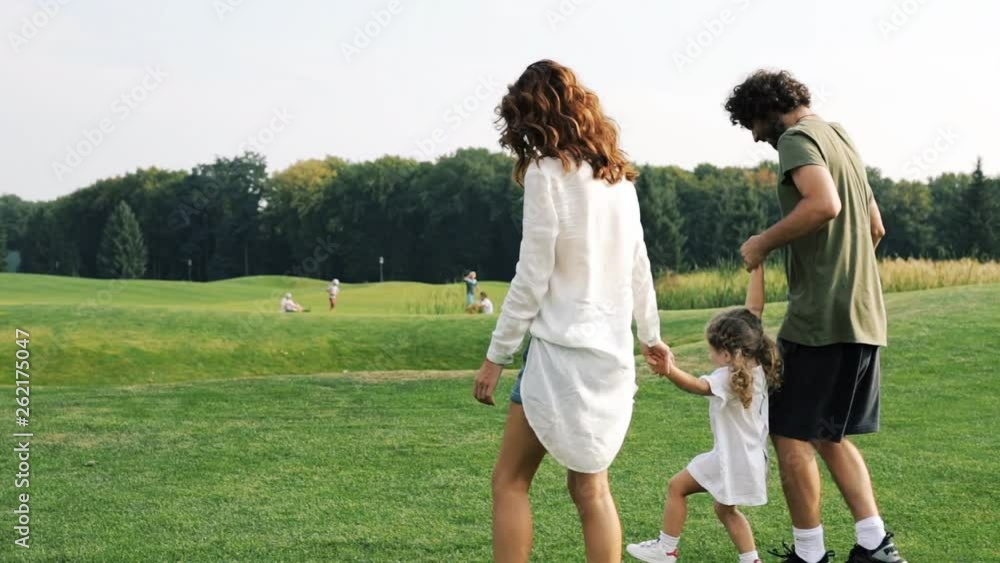 Family with a child walks on a green lawn in the park. Steadicam shot. Family with a child walks on a green lawn in the park. Steadicam shot.