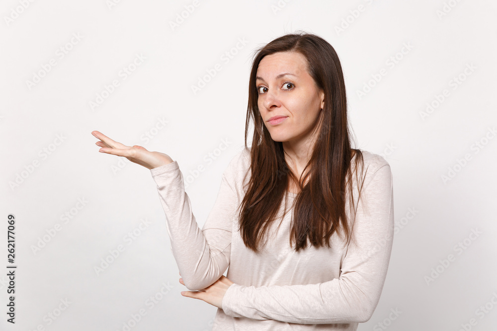 Portrait of bewildered puzzled young woman in light clothes looking camera, pointing hand aside isolated on white background in studio. People sincere emotions, lifestyle concept. Mock up copy space. Portrait of bewildered puzzled young woman in light clothes looking camera, pointing hand aside isolated on white background in studio. People sincere emotions, lifestyle concept. Mock up copy space.
