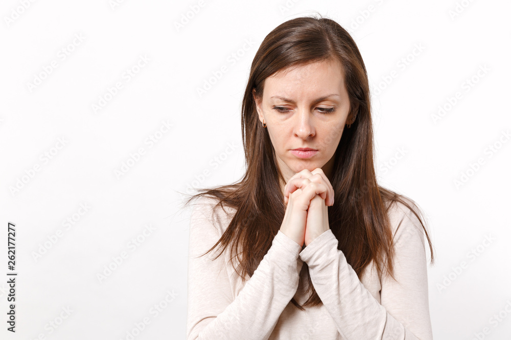 Portrait of pensive young woman in light clothes looking down, holding palms crossed, praying isolated on white background in studio. People sincere emotions, lifestyle concept. Mock up copy space. Portrait of pensive young woman in light clothes looking down, holding palms crossed, praying isolated on white background in studio. People sincere emotions, lifestyle concept. Mock up copy space.