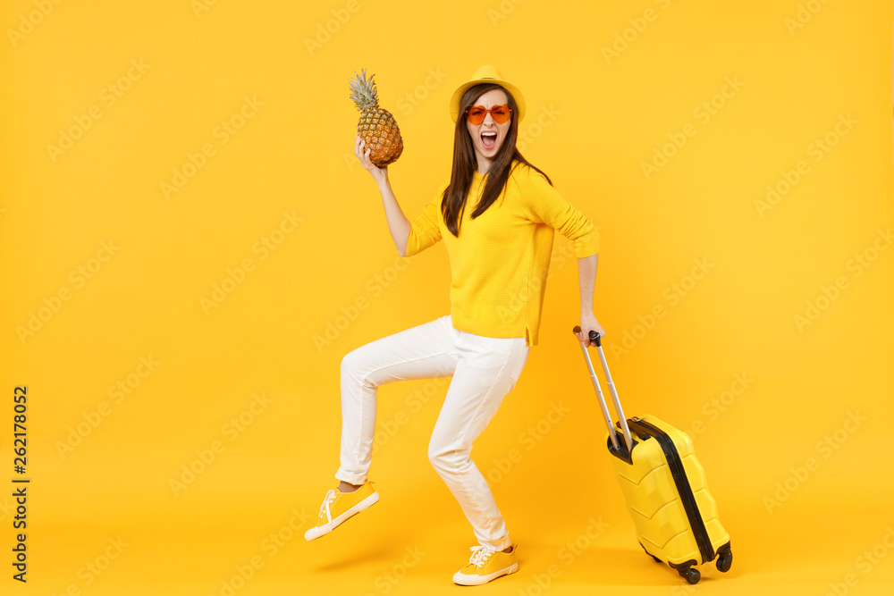 Screaming traveler tourist woman in summer clothes hat hold fresh ripe pineapple fruit isolated on yellow orange background. Passenger traveling abroad on weekends getaway. Air flight journey concept. Screaming traveler tourist woman in summer clothes hat hold fresh ripe pineapple fruit isolated on yellow orange background. Passenger traveling abroad on weekends getaway. Air flight journey concept.