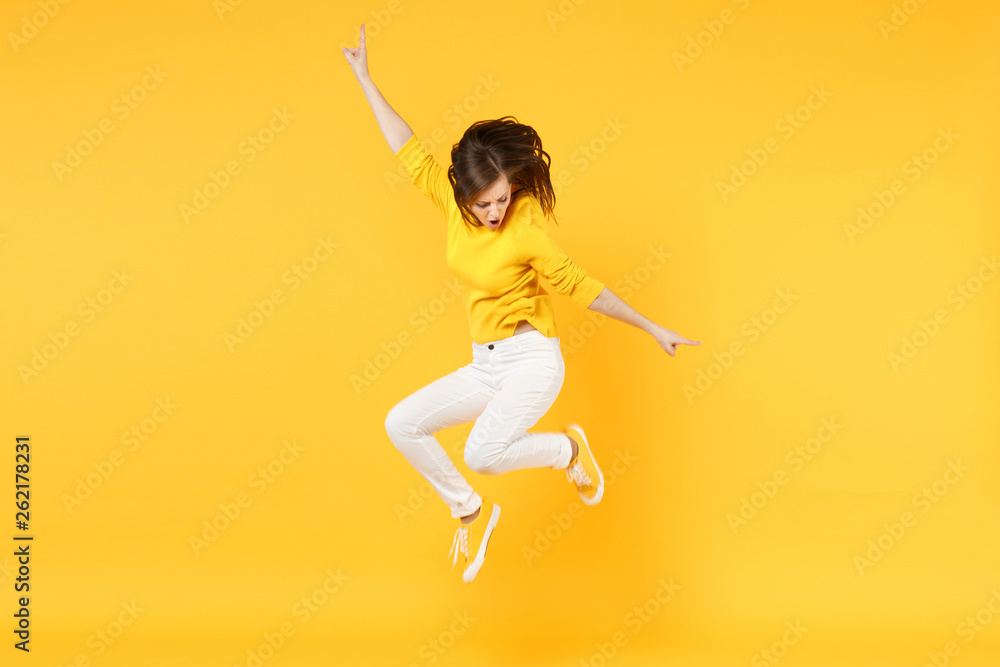 Cheerful funny young woman in summer casual clothes jumping and spreading hands isolated on yellow orange wall background in studio. People sincere emotions, lifestyle concept. Mock up copy space. - obrazy, fototapety, plakaty 