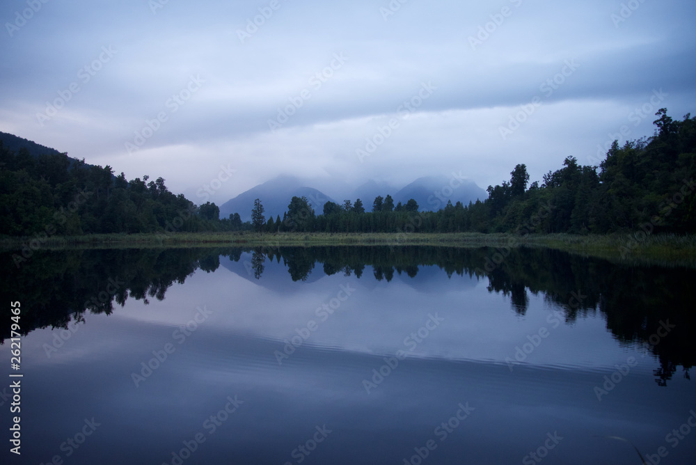 Reflection of trees and mountains on a lake at Fiordland National Park, New Zealand