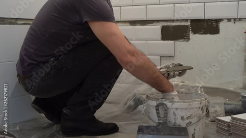 application of tile glue on the tile, for subsequent gluing tiles on the wall in the bathroom