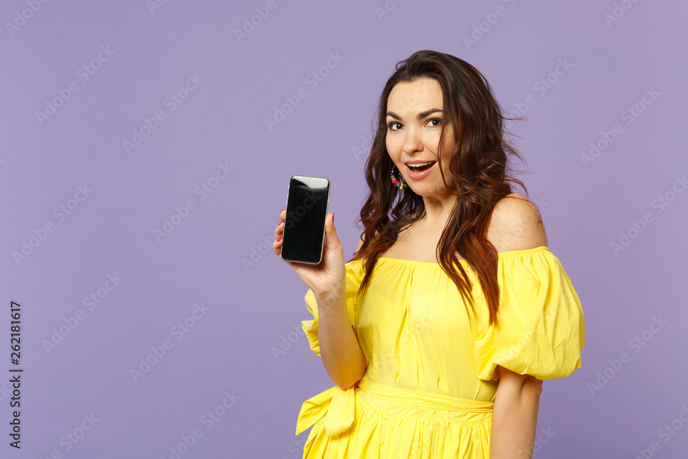 Excited young woman in yellow summer dress holding mobile phone with blank empty screen isolated on pastel violet background in studio. People sincere emotions, lifestyle concept. Mock up copy space. Excited young woman in yellow summer dress holding mobile phone with blank empty screen isolated on pastel violet background in studio. People sincere emotions, lifestyle concept. Mock up copy space.