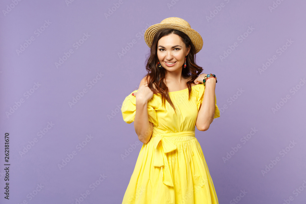 Smiling beautiful young woman in yellow dress, summer hat standing, looking camera isolated on pastel violet wall background in studio. People sincere emotions, lifestyle concept. Mock up copy space. Smiling beautiful young woman in yellow dress, summer hat standing, looking camera isolated on pastel violet wall background in studio. People sincere emotions, lifestyle concept. Mock up copy space.