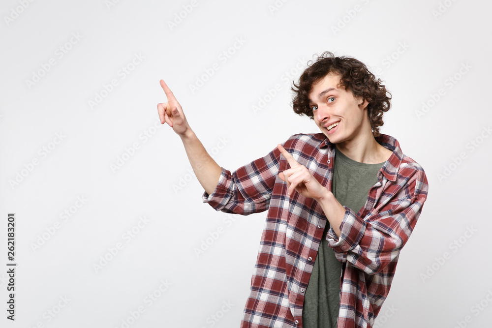 Portrait of cheerful young man in casual clothes looking camera pointing index fingers aside isolated on white wall background in studio. People sincere emotions lifestyle concept. Mock up copy space. Portrait of cheerful young man in casual clothes looking camera pointing index fingers aside isolated on white wall background in studio. People sincere emotions lifestyle concept. Mock up copy space.
