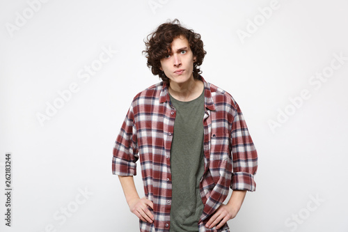 Portrait of perplexed strict young man in casual clothes standing with arms akimbo on waist isolated on white wall background in studio. People sincere emotions, lifestyle concept. Mock up copy space.