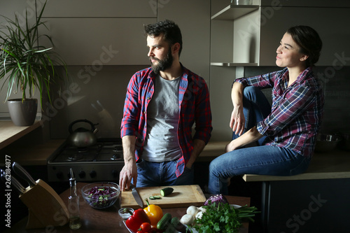 Beautiful young couple in kitchen at home while cooking healthy food. Scene from family life.