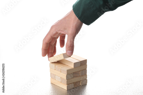 planning strategy concept: man's hand move a toy wooden block from a tower of blocks with copy space for your text