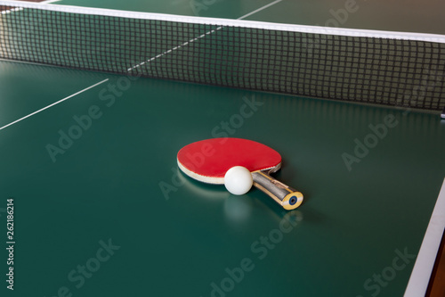ping-pong racket and a ball on a green table. ping-pong net.