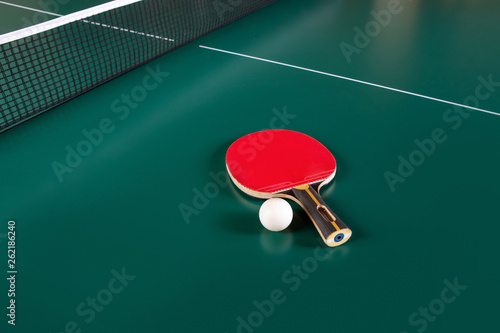 ping-pong racket and a ball on a green table. ping-pong net.