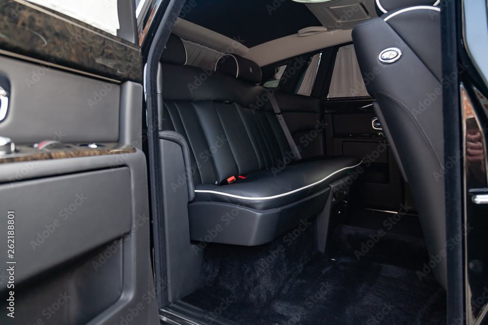 Interior view of new a very expensive car, a long black limousine with rear seats and opened door on parking
