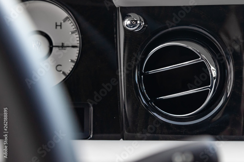A close-up view of a part of the interior of a modern luxury car with a view of the ventilation deflector of the stove for heating and cooling the passenger compartment with black trim elements