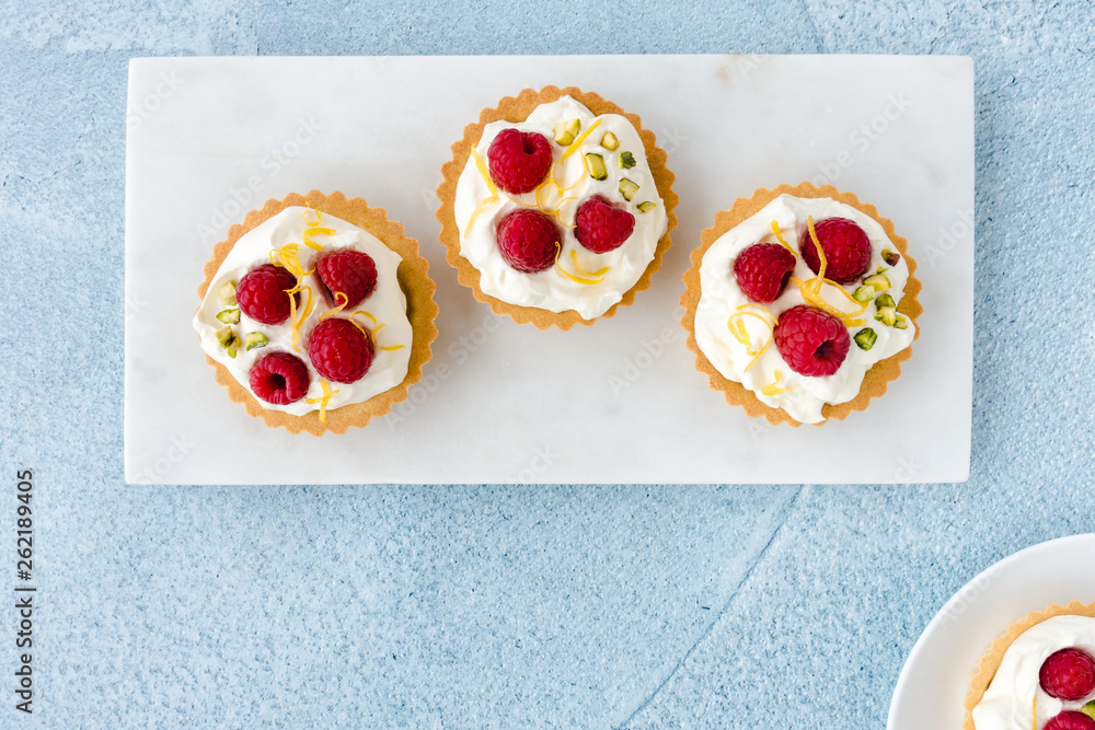 Closeup of Raspberry Fruit Tartlets on White Marble and Plate