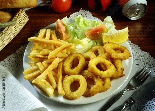 Un plato de calamares a la romana, ensalada y patatas fritas.
