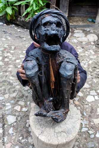 Wamena, Indonesia. Old man from Dani tribe holding mummy of a village elder. Dugum Dani Village. Baliem Valley Papua, Irian Jaya, Indonesian New Guinea photo