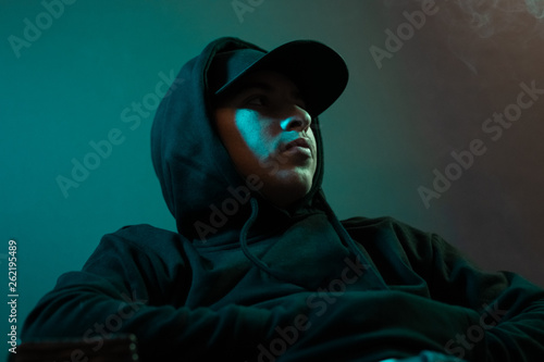 young cool rapper with black hoodie and cap looking sideways