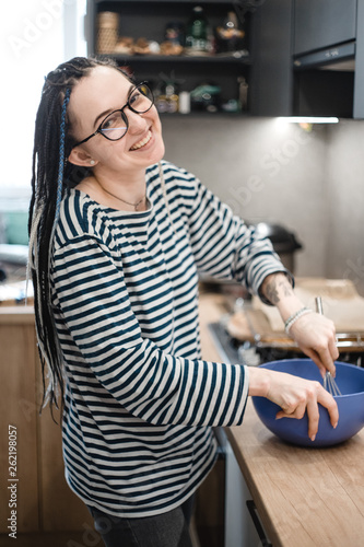 smiling dreadlock girl  in striped blouse cooking on the kitchen