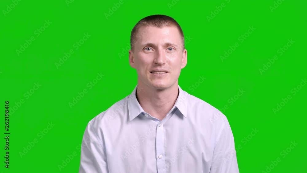 Young man talking to camera with green screen in background.