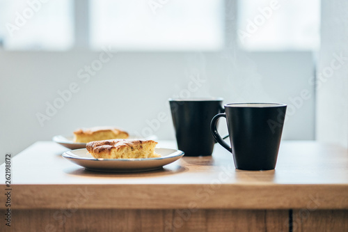black cup of coffee and apple cake on wooden table 