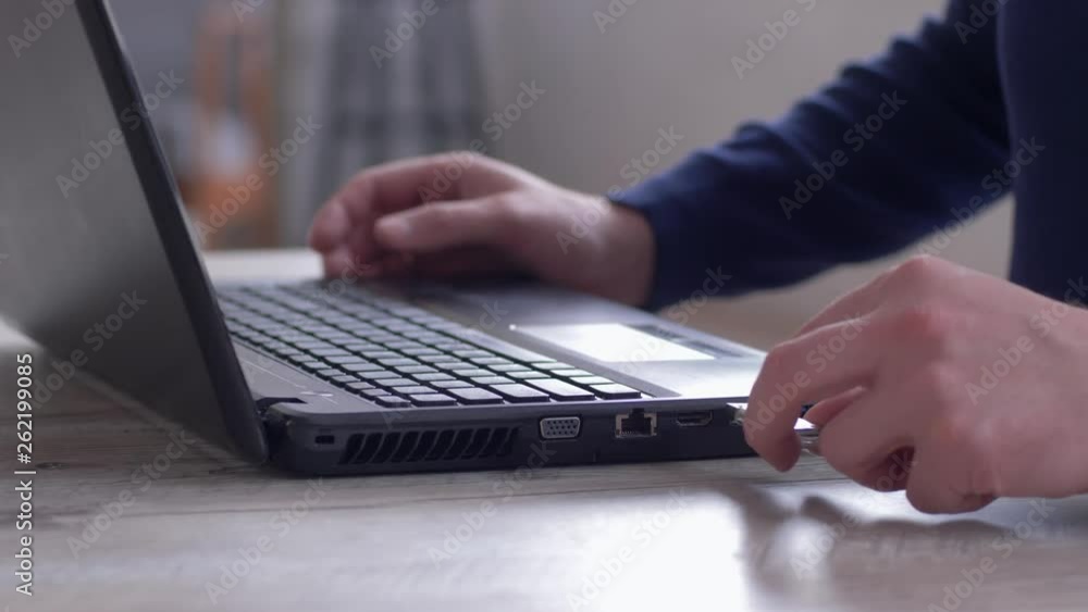 male hands uses laptop and copying information to usb flash drive sitting at the table male hands uses laptop and copying information to usb flash drive sitting at the table