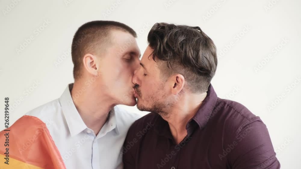 Young gay male couple passionately kiss with pride rainbow flag. Pull down flag. Happy gay friendship, relationship, pride concept. Young gay male couple passionately kiss with pride rainbow flag. Pull down flag. Happy gay friendship, relationship, pride concept.