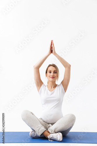 Pregnant yoga fitness woman posing isolated over white wall background make exercises.