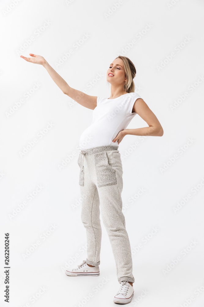 Beautiful young pregnant woman posing isolated over white wall background.