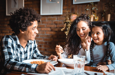 Happy african american family eating lunch together at restaurant and having fun