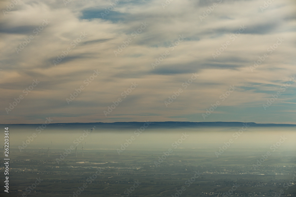 Landschaft Rheinebene mit Windrädern unter einer Nebeldecke und Wolkendecke