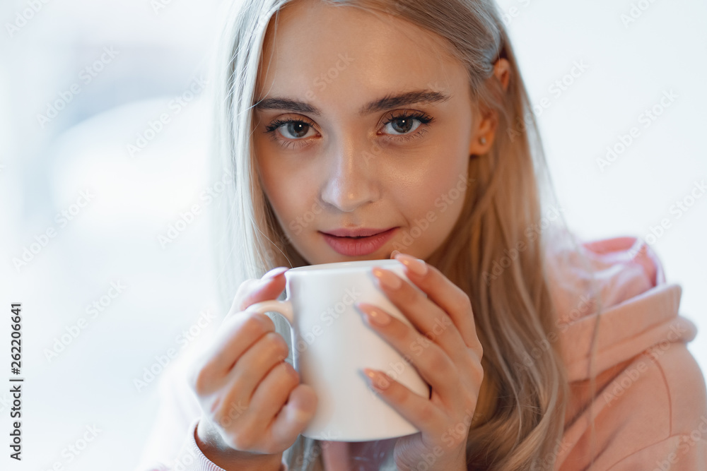 An elf alike, young girl enjoying a cup of coffee or milk while sitting by the window indoors An elf alike, young girl enjoying a cup of coffee or milk while sitting by the window indoors